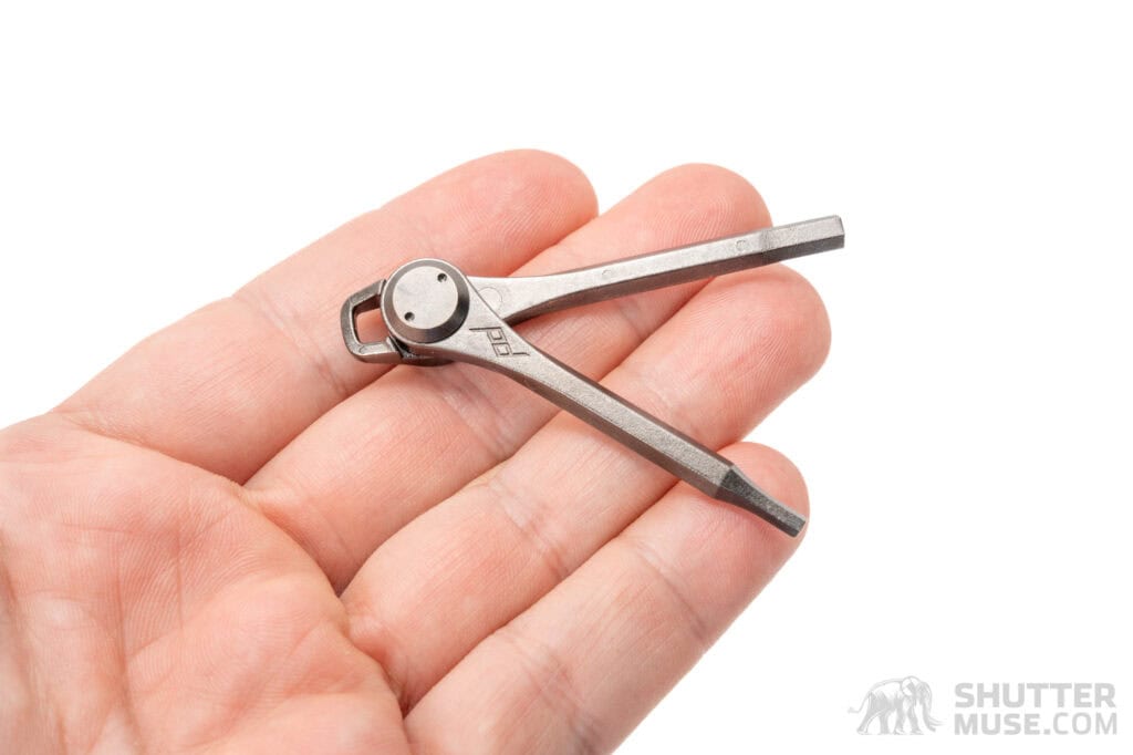 a peak design tripod tool resting in a hand on a white background